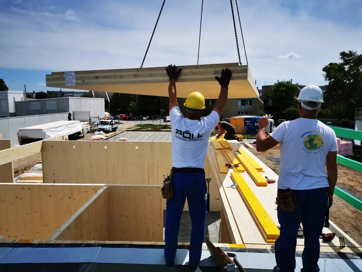Two persons assembling wooden elements at a construction site. 
