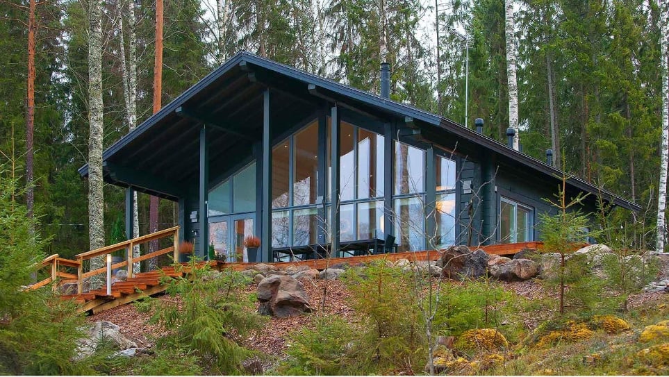 Ollikainen Hirsitalot -yrityksen suunnittelema puutalo metsäisessä ympäristössä.
