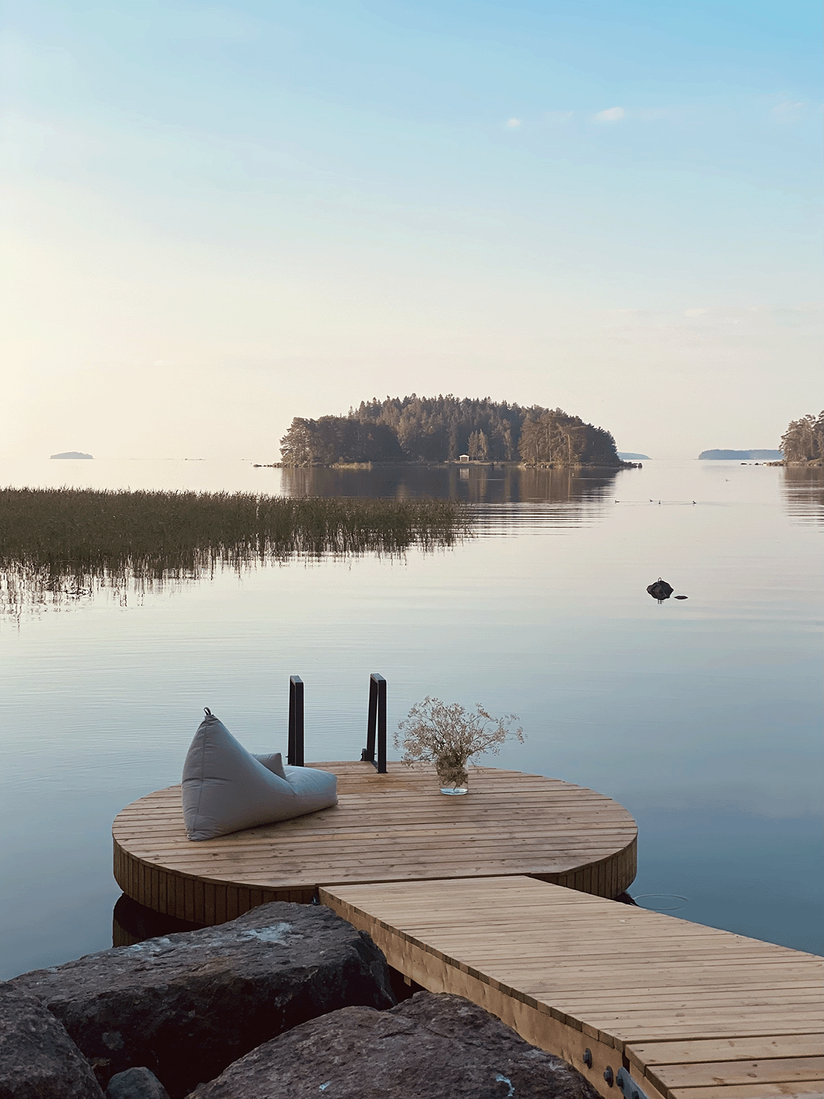 Circular floating Lounge pier on calm water at a Finnish lakeside.